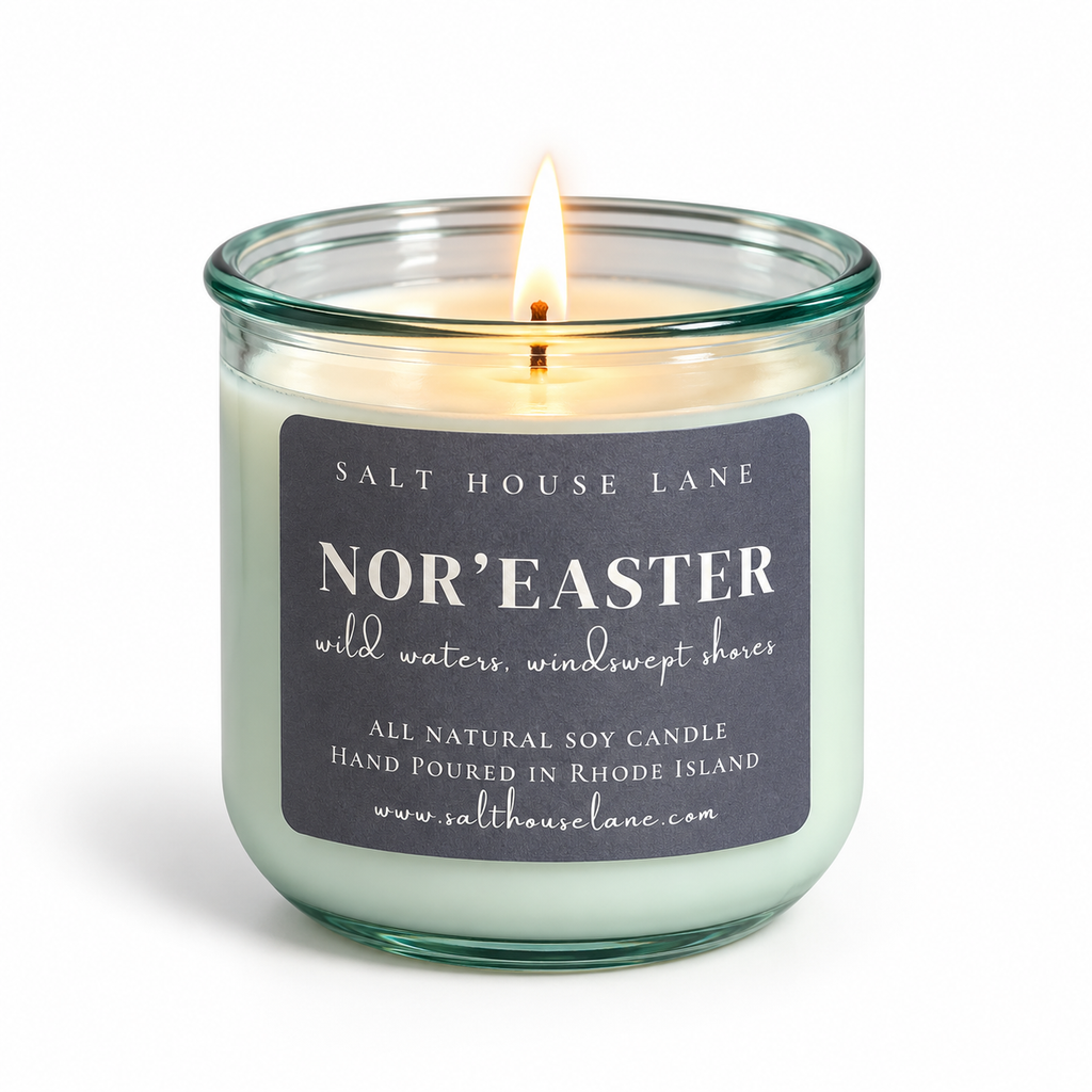 A lit soy candle in a clear glass jar with a dark charcoal label reading 'SALT HOUSE LANE NOR'EASTER' on a white background.
